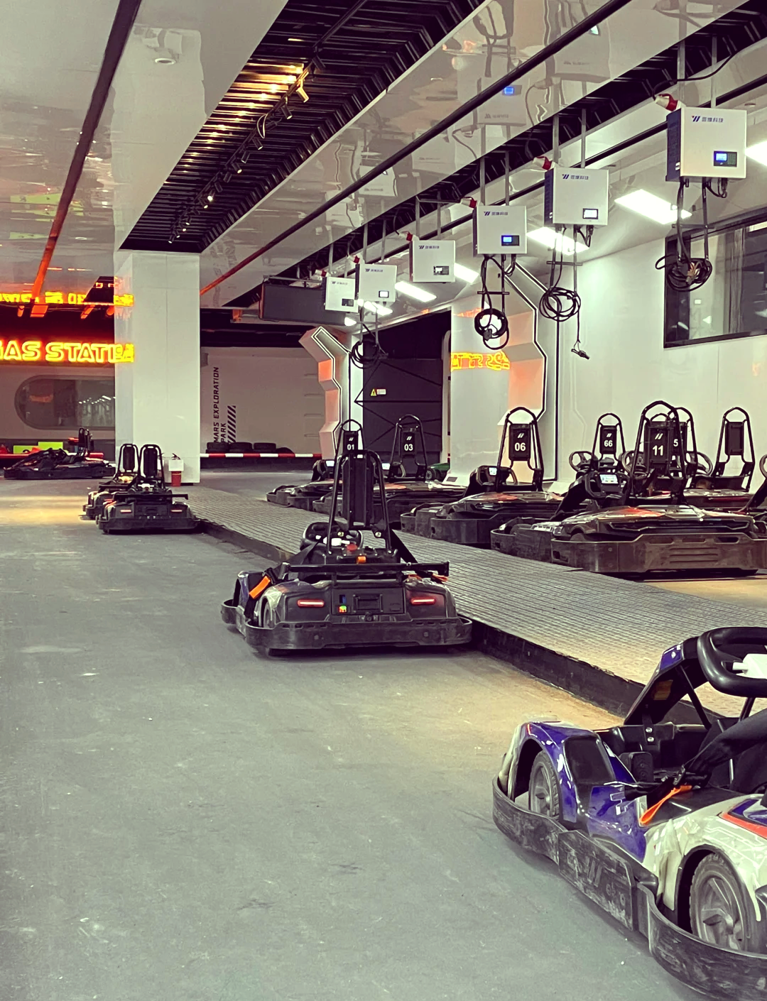 Organized indoor pit lane setup with multi-unit battery charging stations and boarding gates