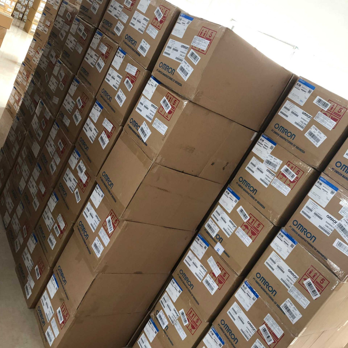 Aisle view of factory-sealed carton stacks in our warehouse