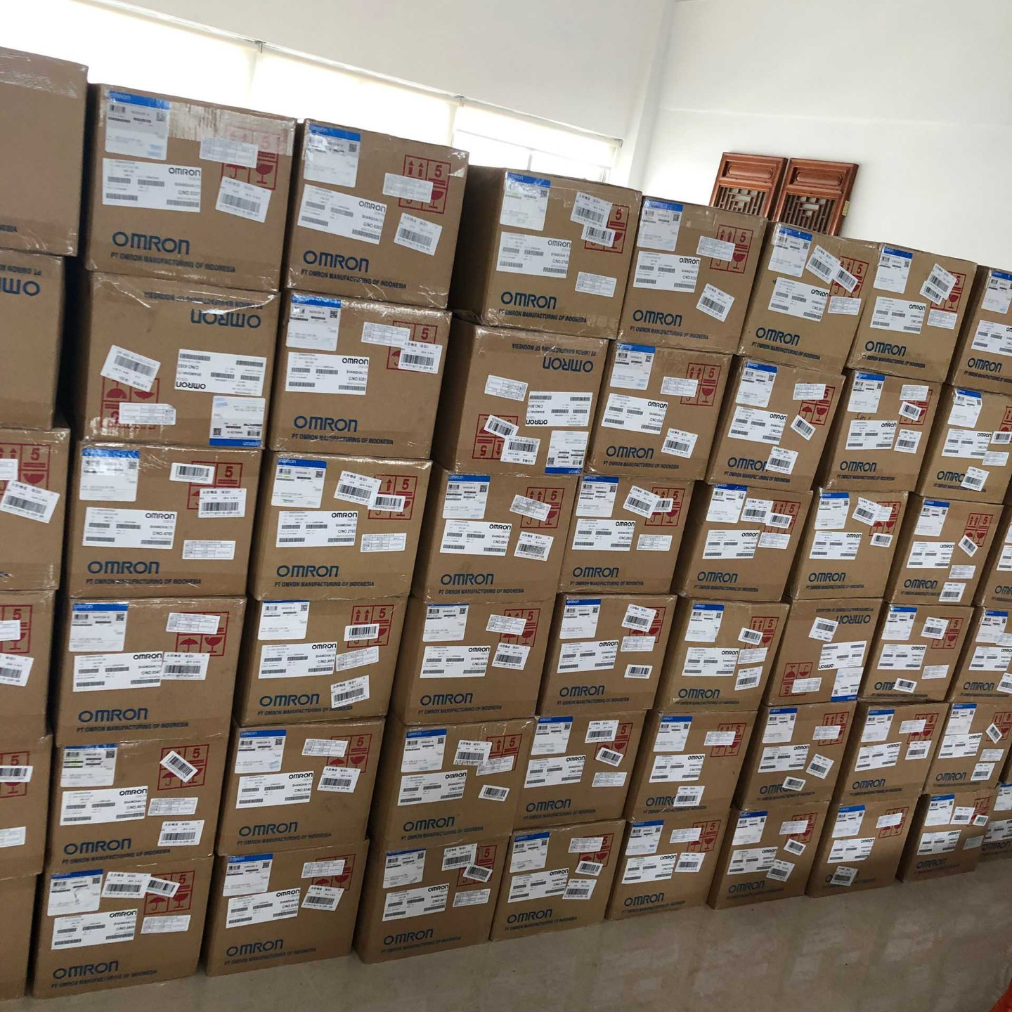 Wall of stacked OMRON original cartons in our warehouse