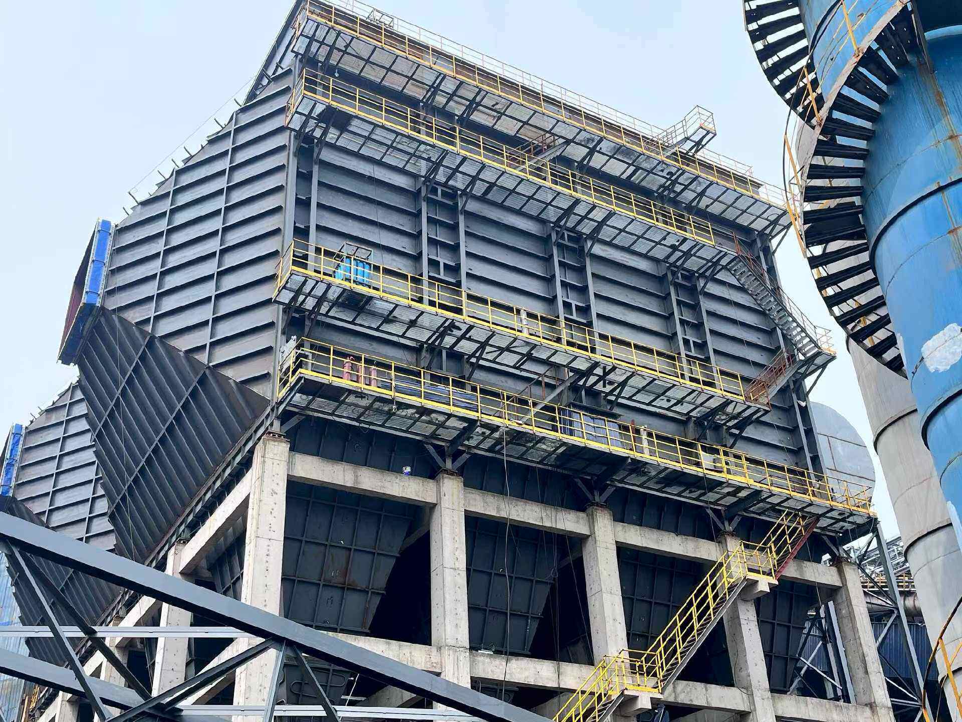 Large grey electrostatic precipitator casing with walkways and hoppers on a concrete frame
