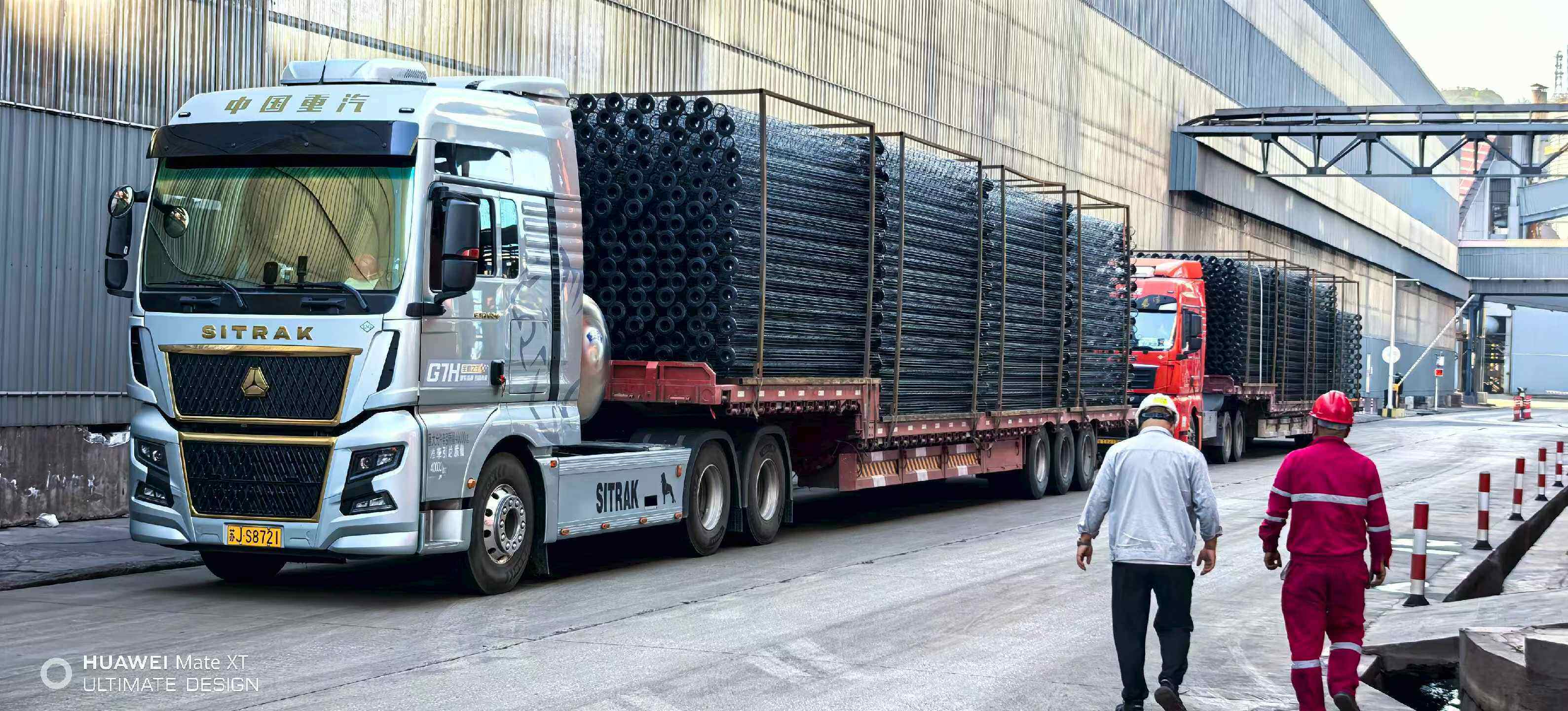 Flatbed trucks loaded with cages of filter bags leaving the factory yard for export shipment