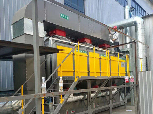 Worker on the platform of an activated carbon adsorption and catalytic combustion unit with insulated ducts during installation