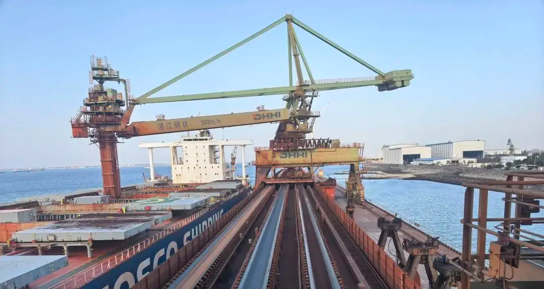 Bulk cargo ship loader boom and belt conveyor gallery along a port terminal pier