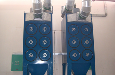 Two vertical cartridge dust collectors with round inspection covers and top exhaust ducts
