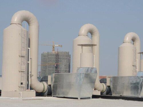 Vertical scrubber stack with curved inlet duct and fan housing installed on a plant roof