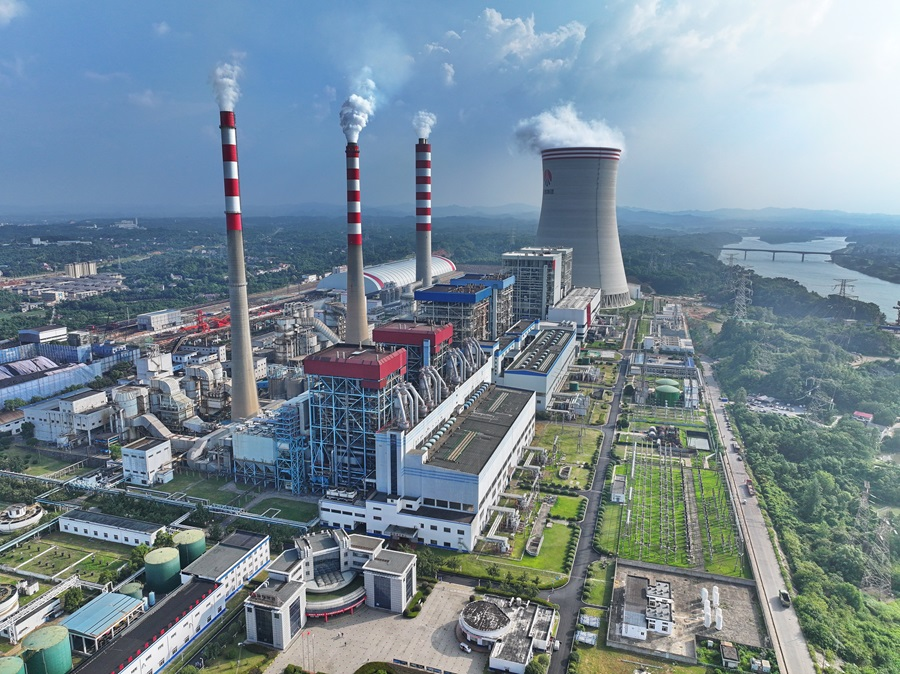 Aerial view of a coal fired power plant with striped stacks, cooling tower, boiler house and switchyard