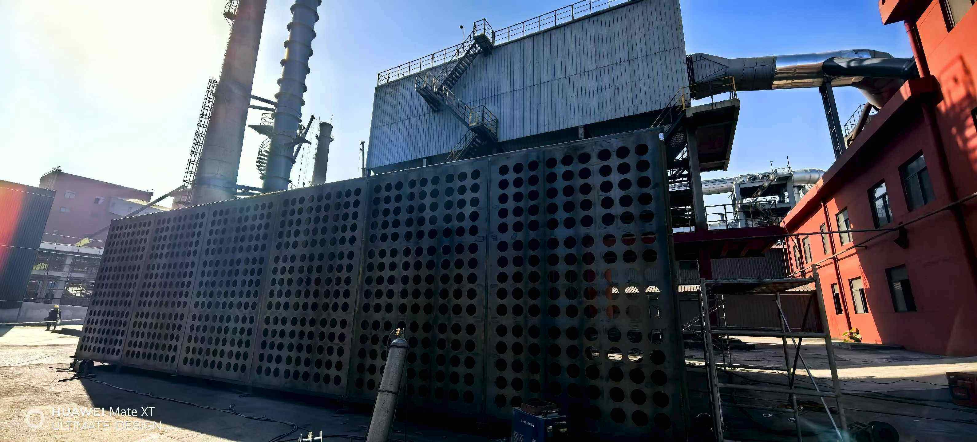 Perforated steel distribution panels staged on the ground in front of the collector body and stacks