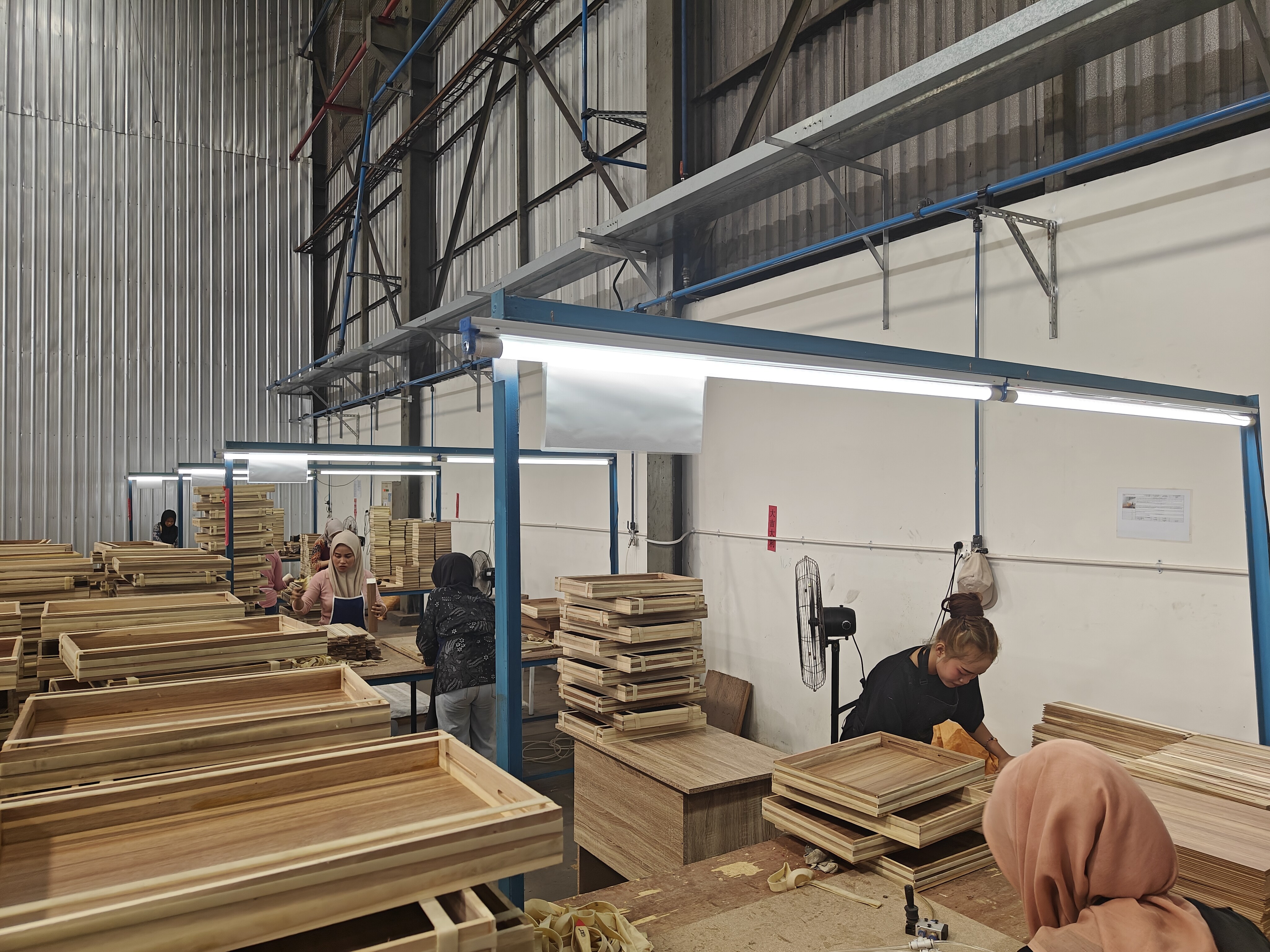 Workers assembling wooden trays at workstations