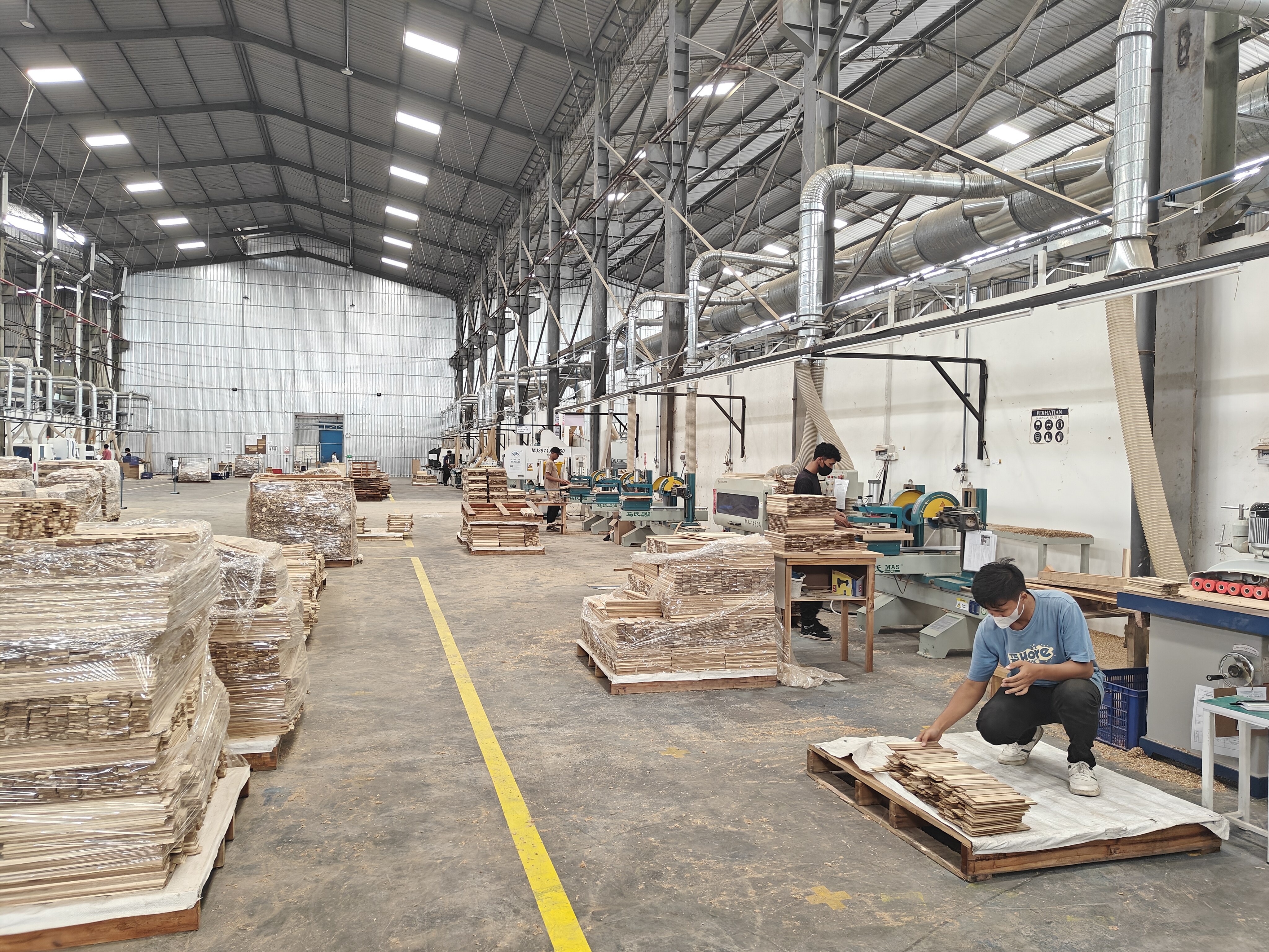 Workers organizing wooden materials in factory warehouse
