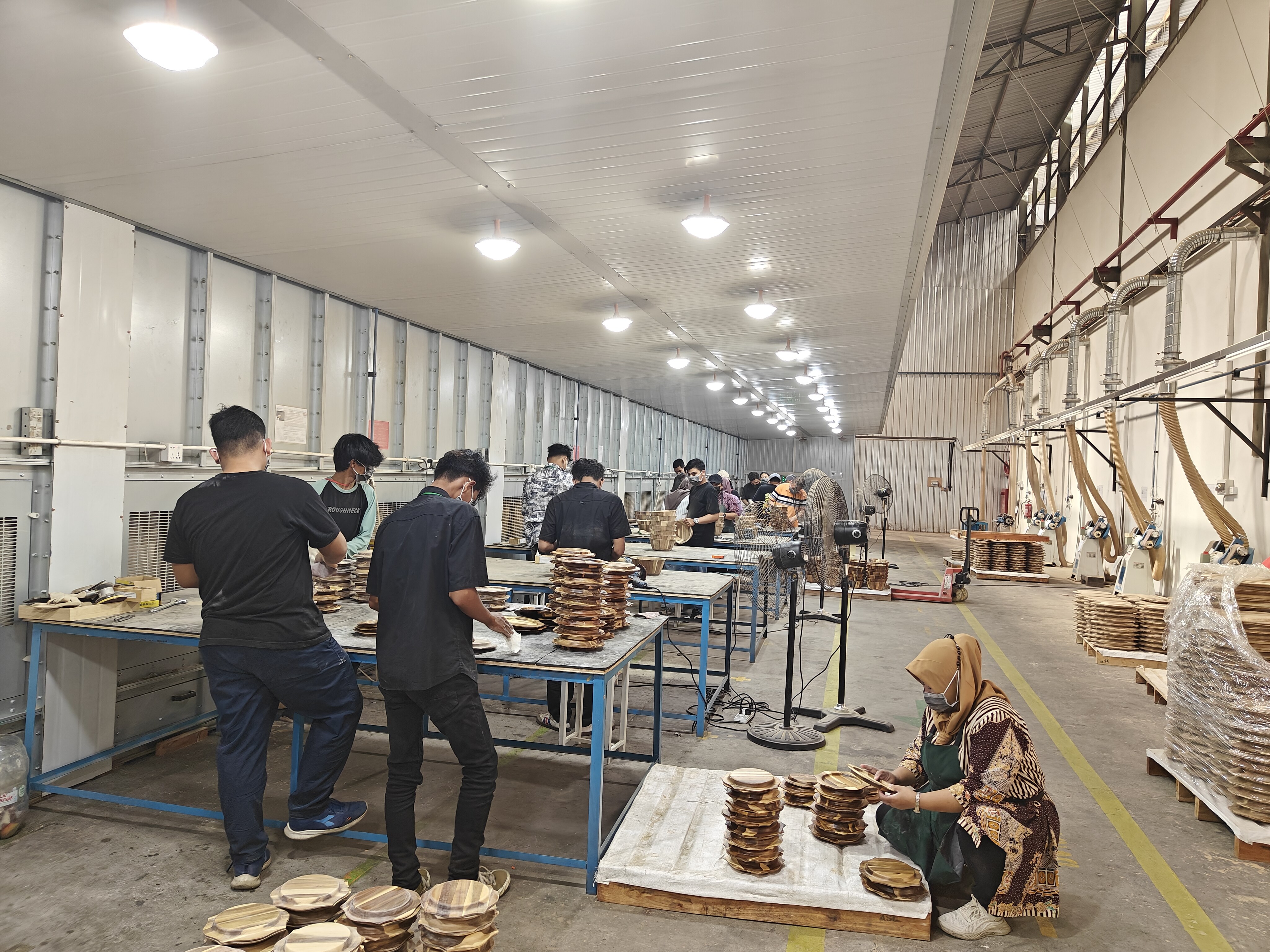 Workers assembling wooden plates at workstations