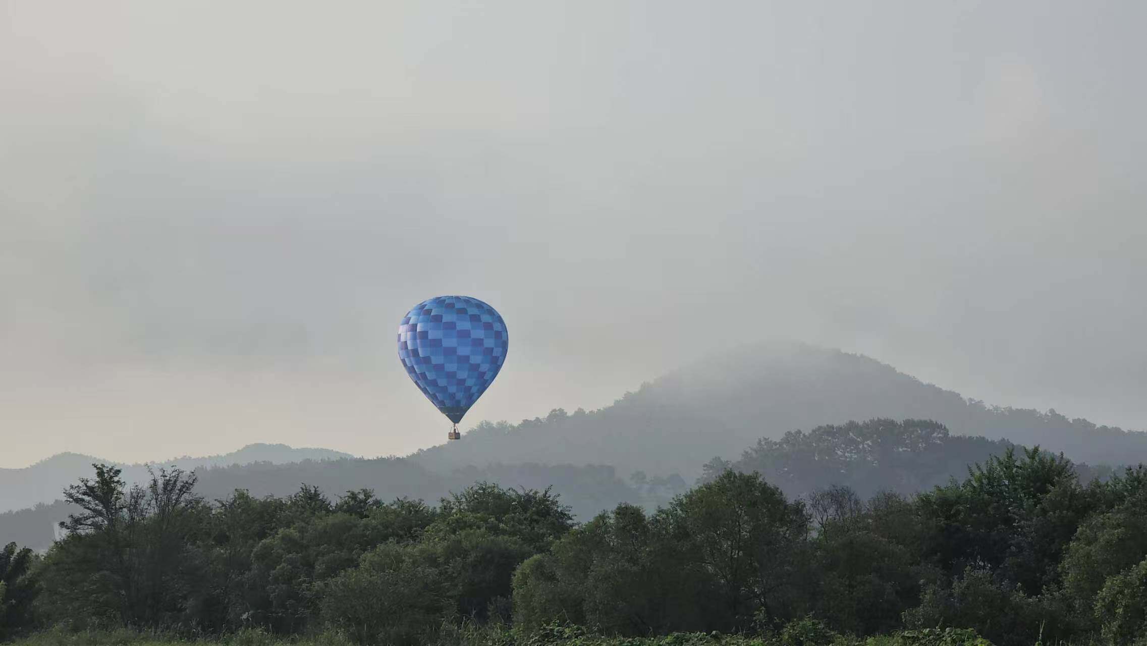 Blue Square Passenger Hot Air Balloon – Blue square passenger hot air balloon with distant mountains in the background, ideal for scenic sightseeing flights.