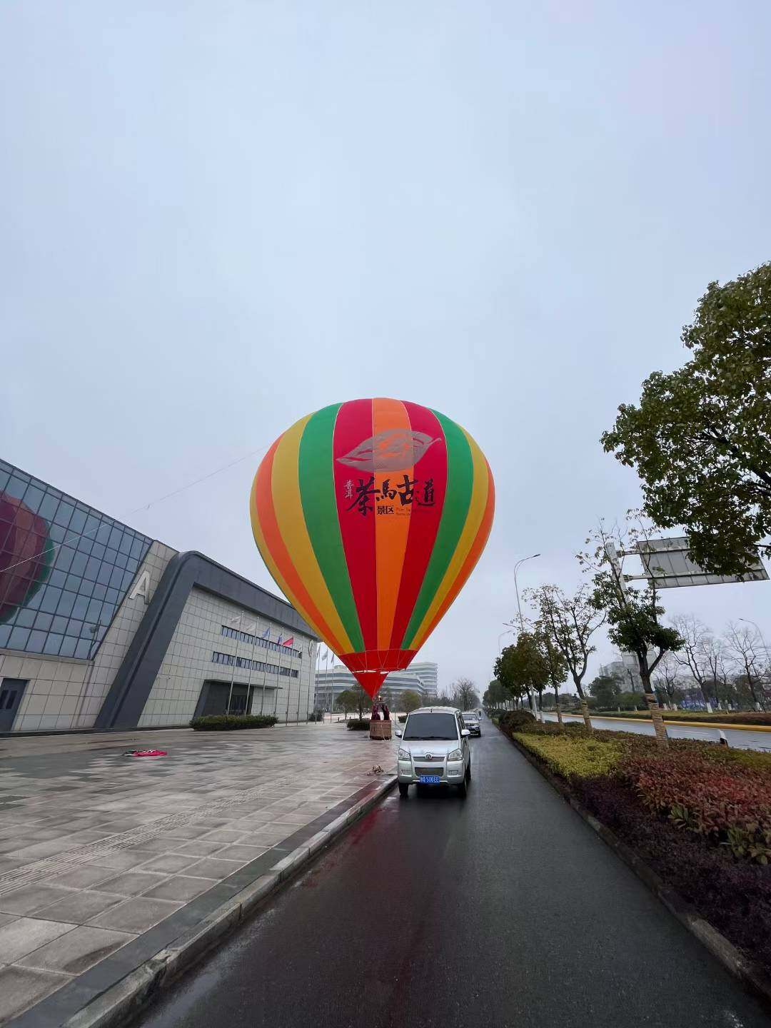 Tea Horse Road Scenic Area Passenger Hot Air Balloon – Custom hot air balloon for the Tea Horse Road Scenic Area featuring red, green, yellow, and orange vertical stripes. Displays the scenic area logo; ideal for sightseeing, tourism promotion, and brand marketing with customizable logo options.