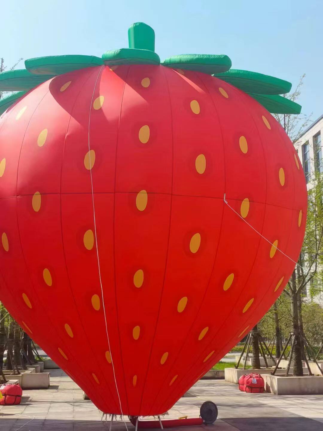 Strawberry-shaped tethered balloon – Red body with green leaves; ideal for fruit-themed events, family activities, and scenic area displays. Vibrant colors.