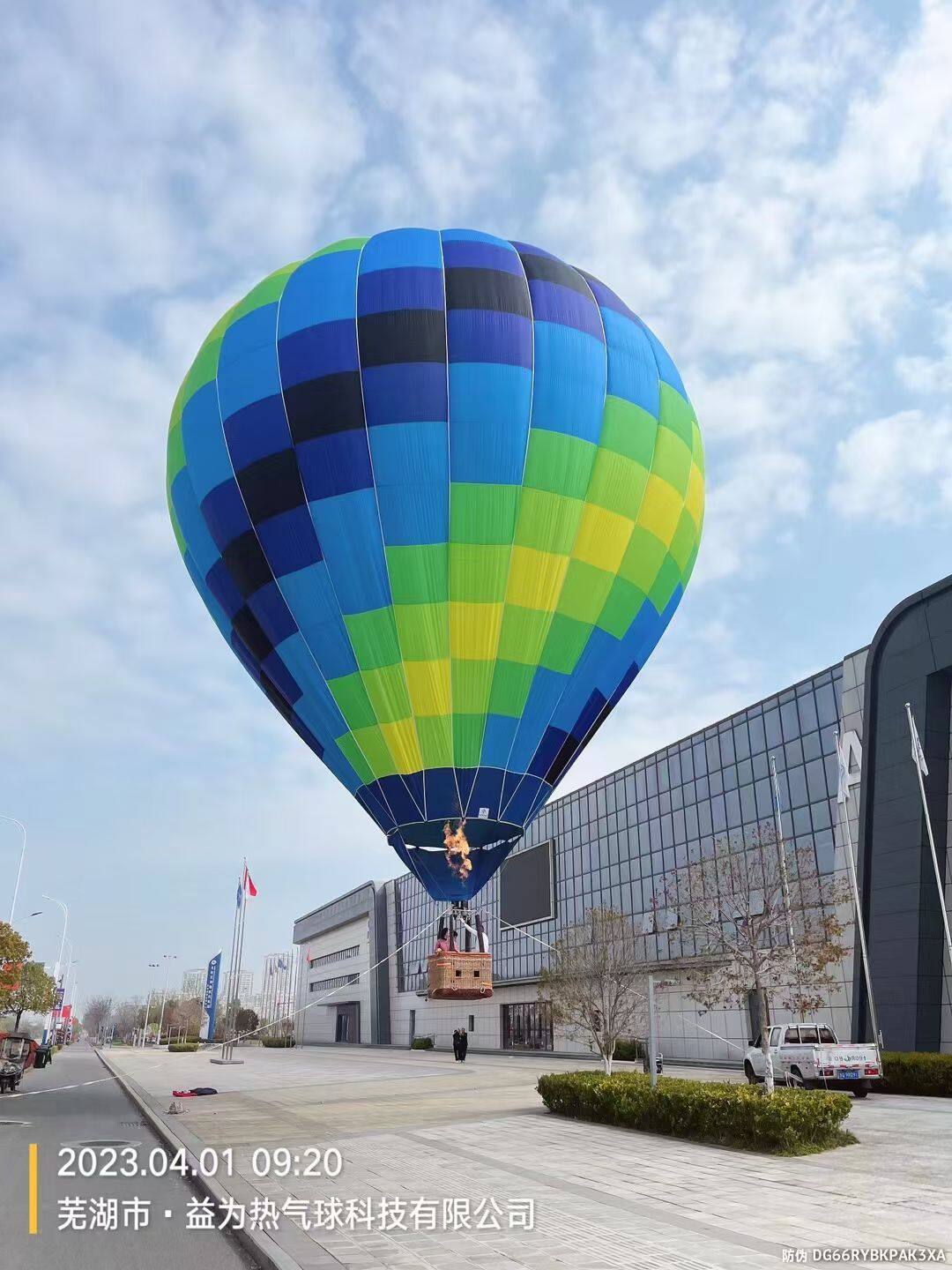 Blue Green Yellow Striped Manned Hot Air Balloon at Wuhu - Manned Hot-Air Balloons by Yiwei Balloons - Blue green and yellow striped manned hot air balloon flying at Wuhu Yiwei Balloons facility with modern building background.