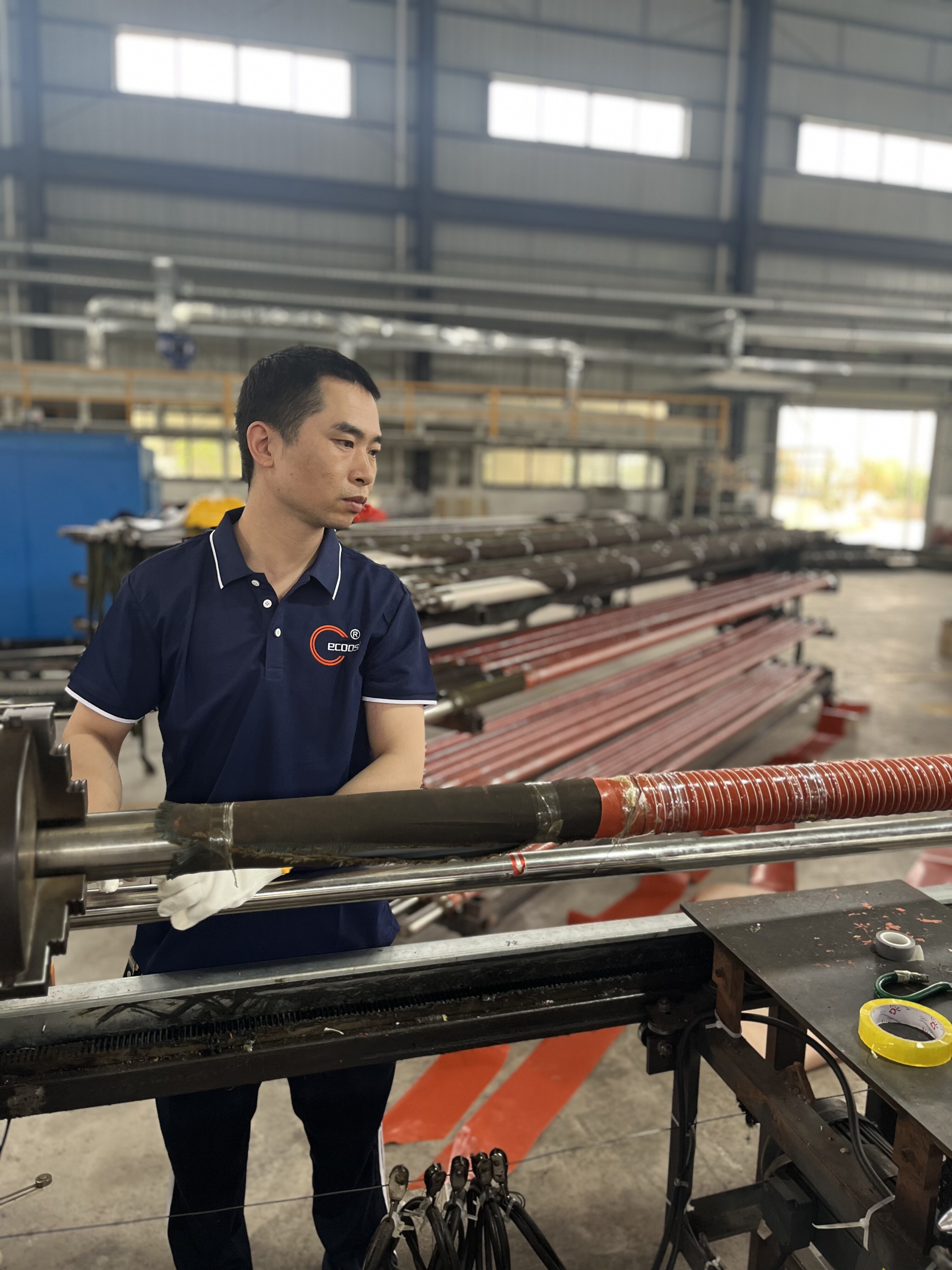 Worker operating duct hose production line in factory