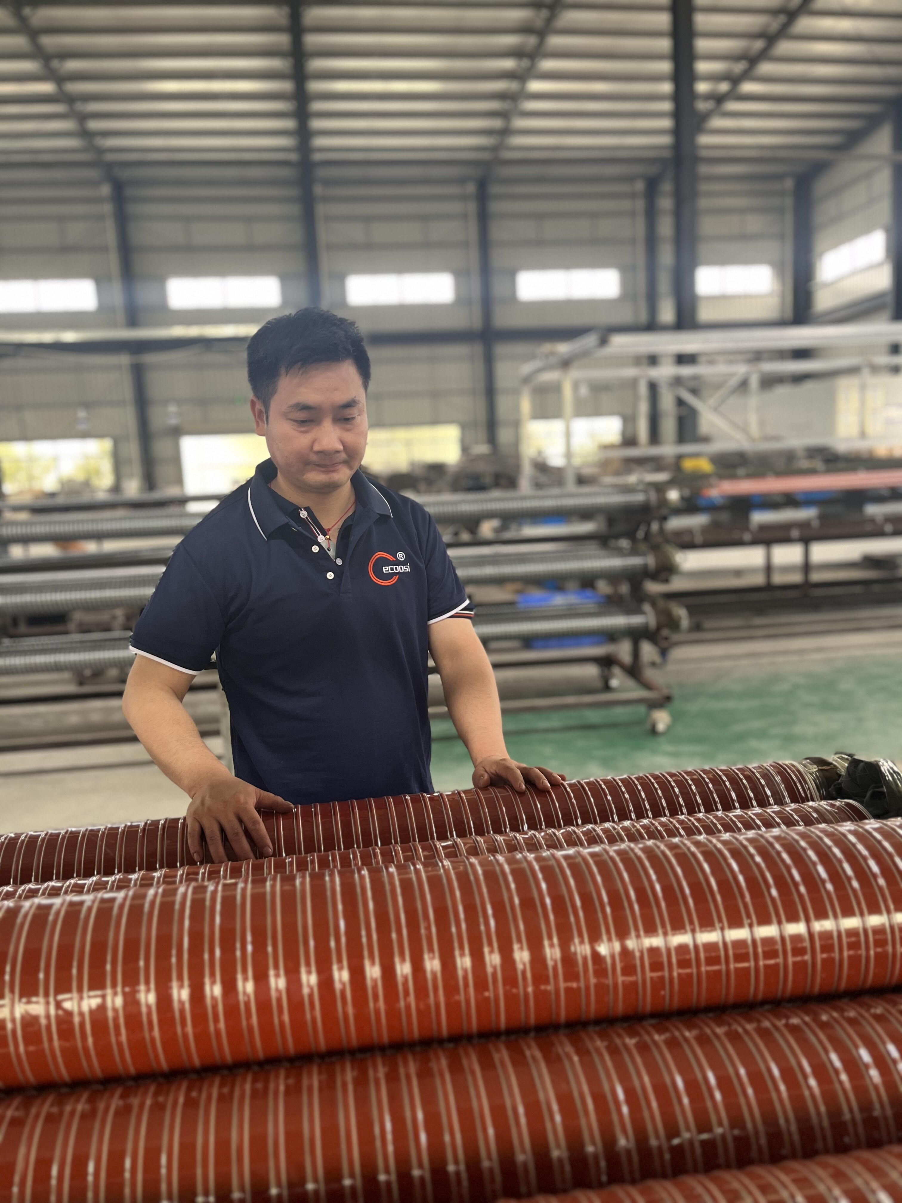 Worker inspecting finished flexible duct products in factory