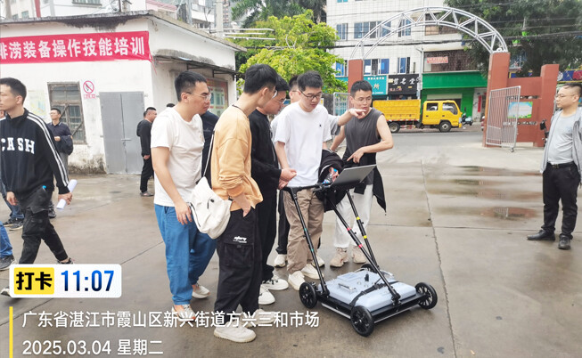A technician guides a trainee in operating the SL-GPR subsurface pipe detector.