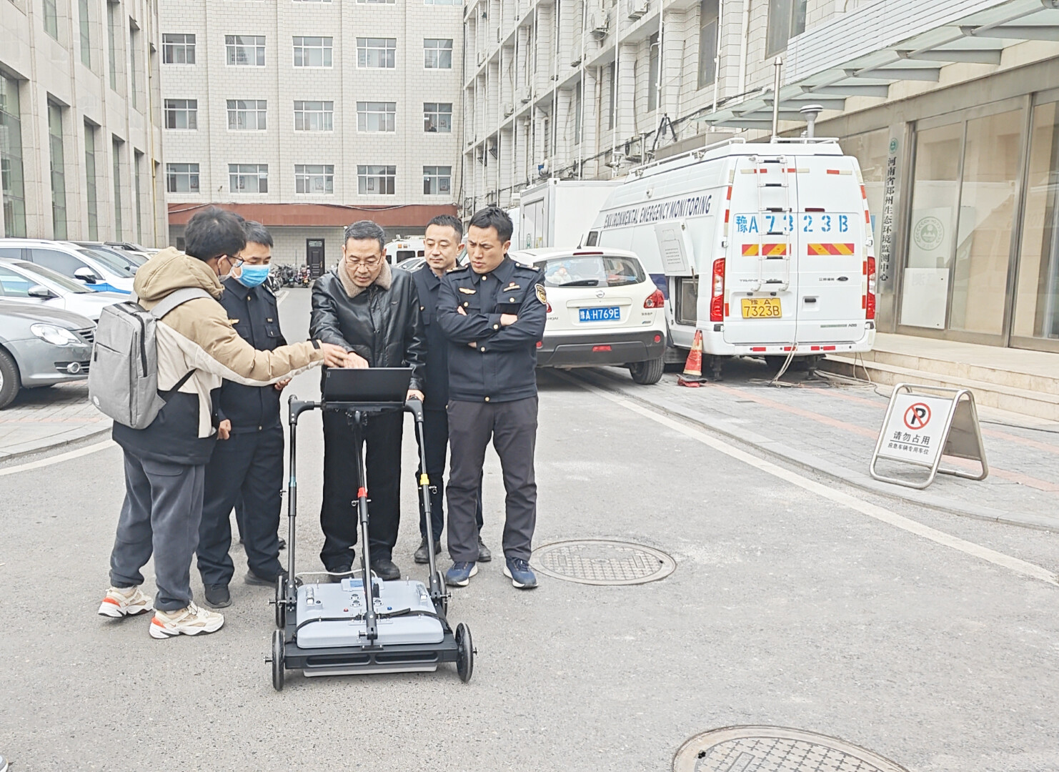 A technician demonstrates device operation to law enforcement officers outdoors.