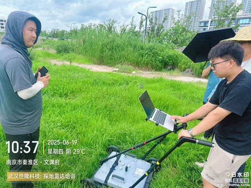 A technician provides on-site guidance to trainees operating the SL-GPR ground-penetrating radar equipment on an outdoor grassy field.