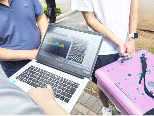 A technician displays ground-penetrating radar 3D imaging data to a North Korean delegation using a laptop.