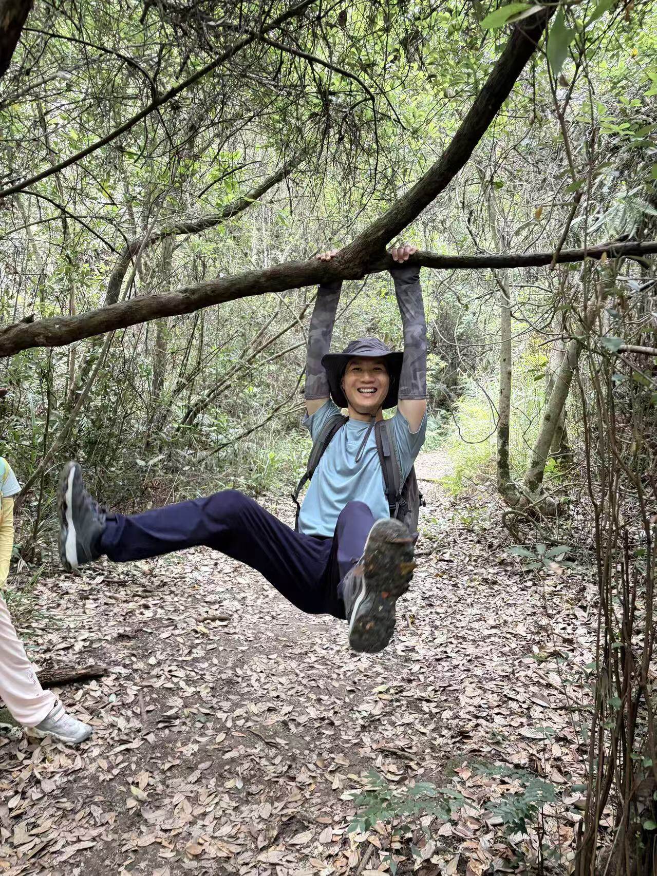 Person hanging from tree branch on trail