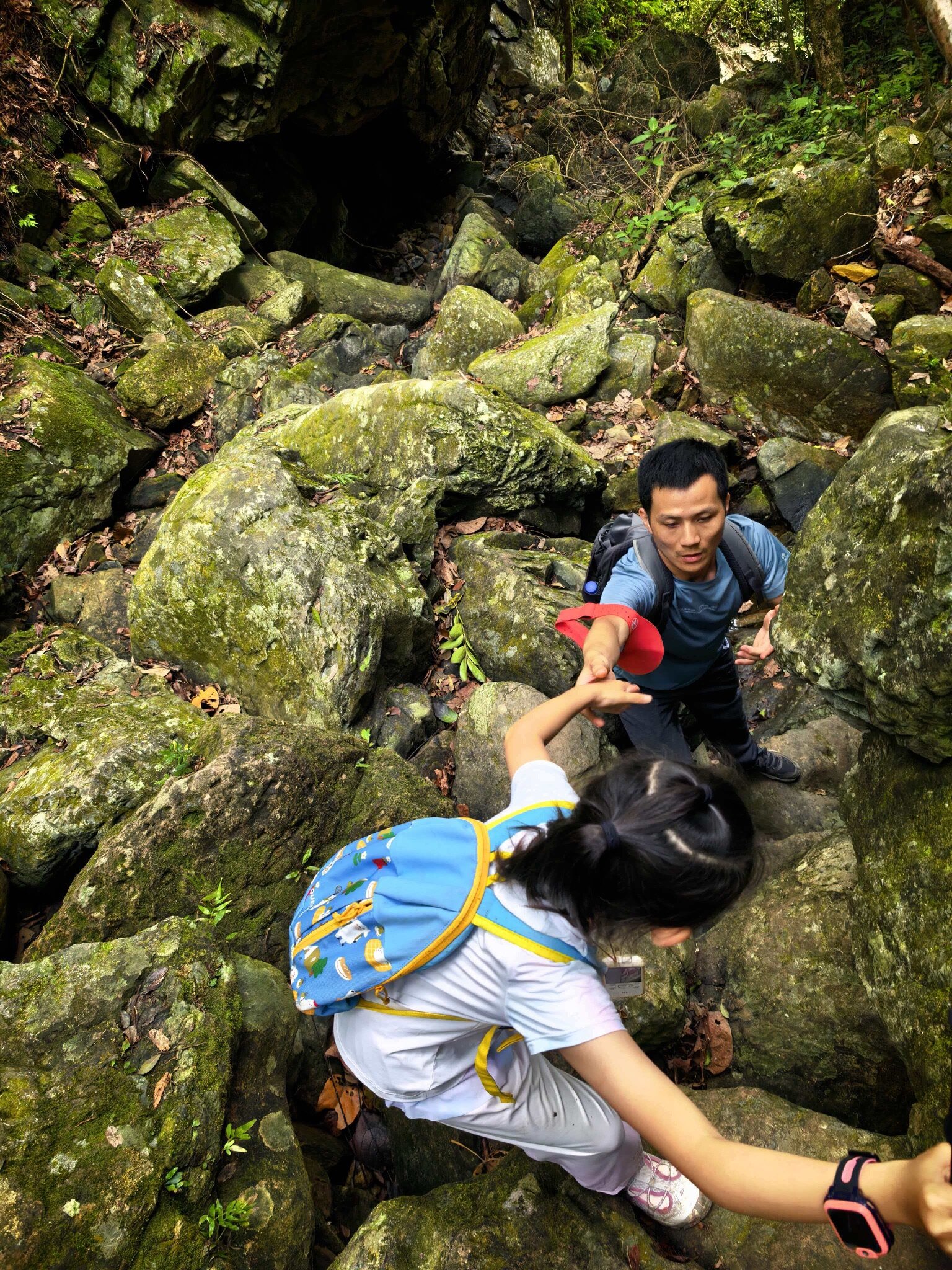 Hikers helping each other on rocky scramble trail