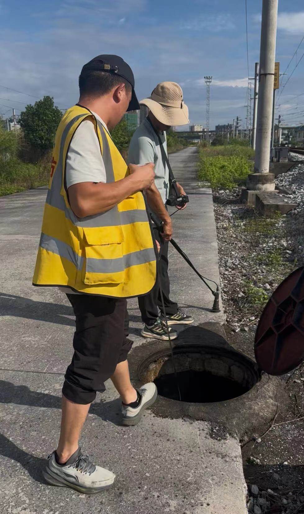 持证测漏工程师穿铁路反光背心,轨道旁检查井开展消防管网声波扫测