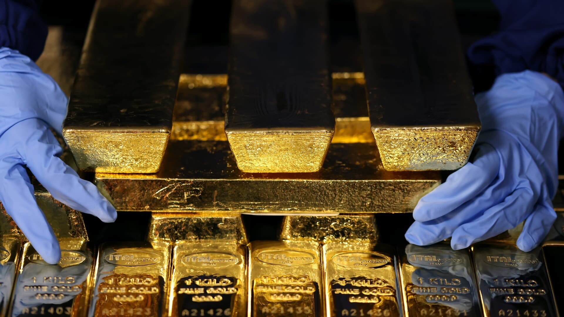 Gold bars held by gloved hands