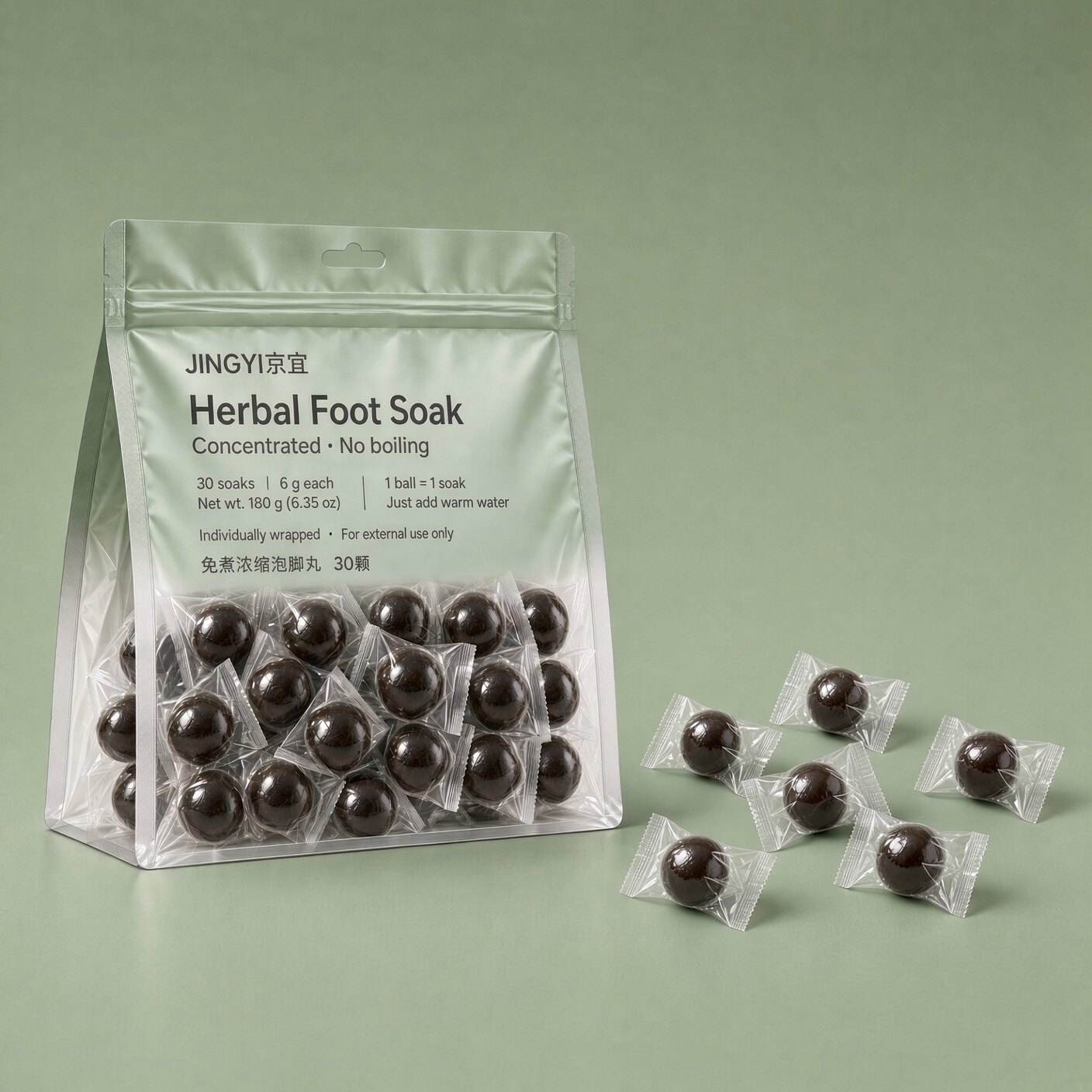 Three JINGYI retail pouches and gloved hands holding individually wrapped foot soak balls