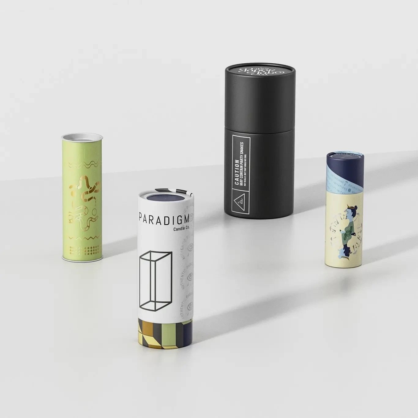 Hands rotating a matte black paper tube so the brushed-gold foil band and embossed lines catch the studio light
