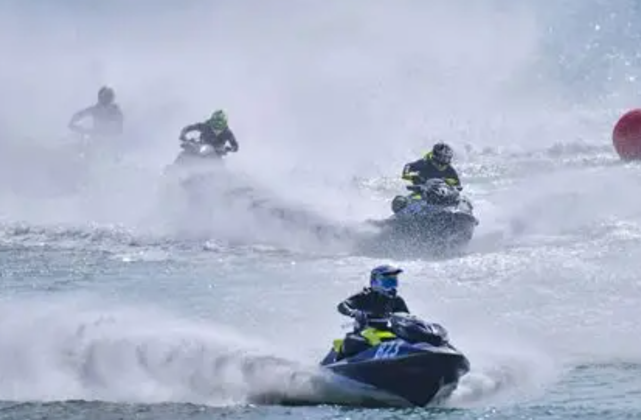 Multiple jet ski athletes splashing through the water