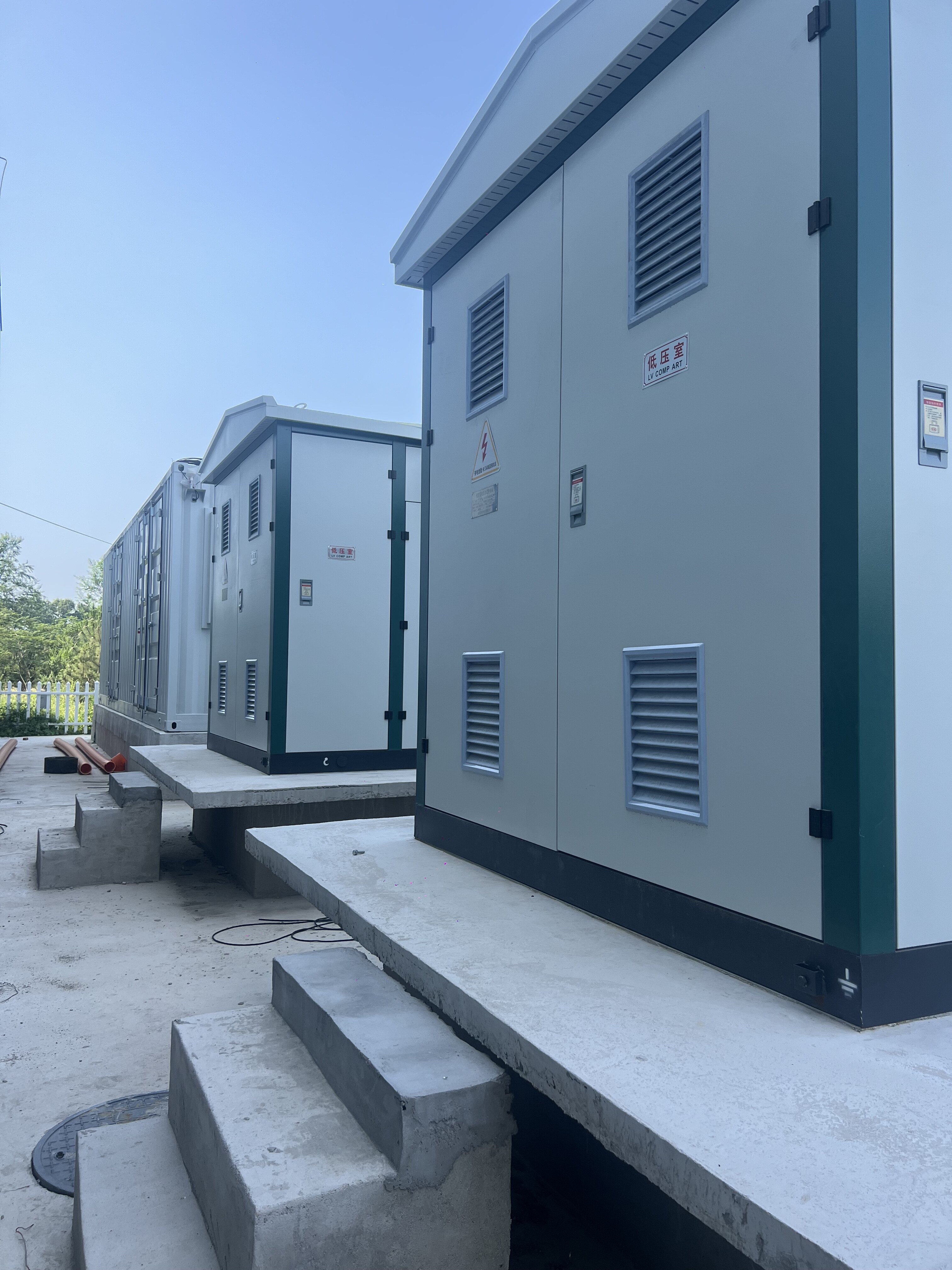 Multiple energy storage container units with LV COMP ART labeling on concrete platforms