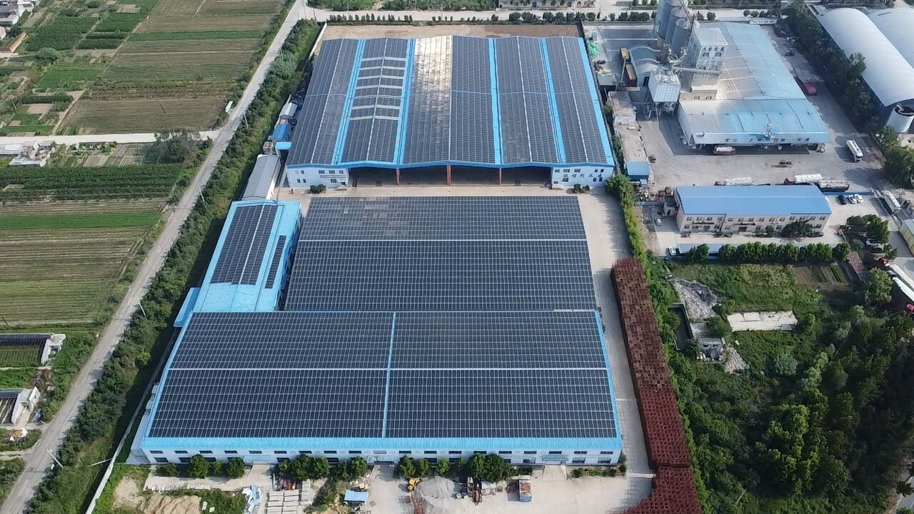 Aerial view of large industrial warehouse with extensive rooftop solar panel installation