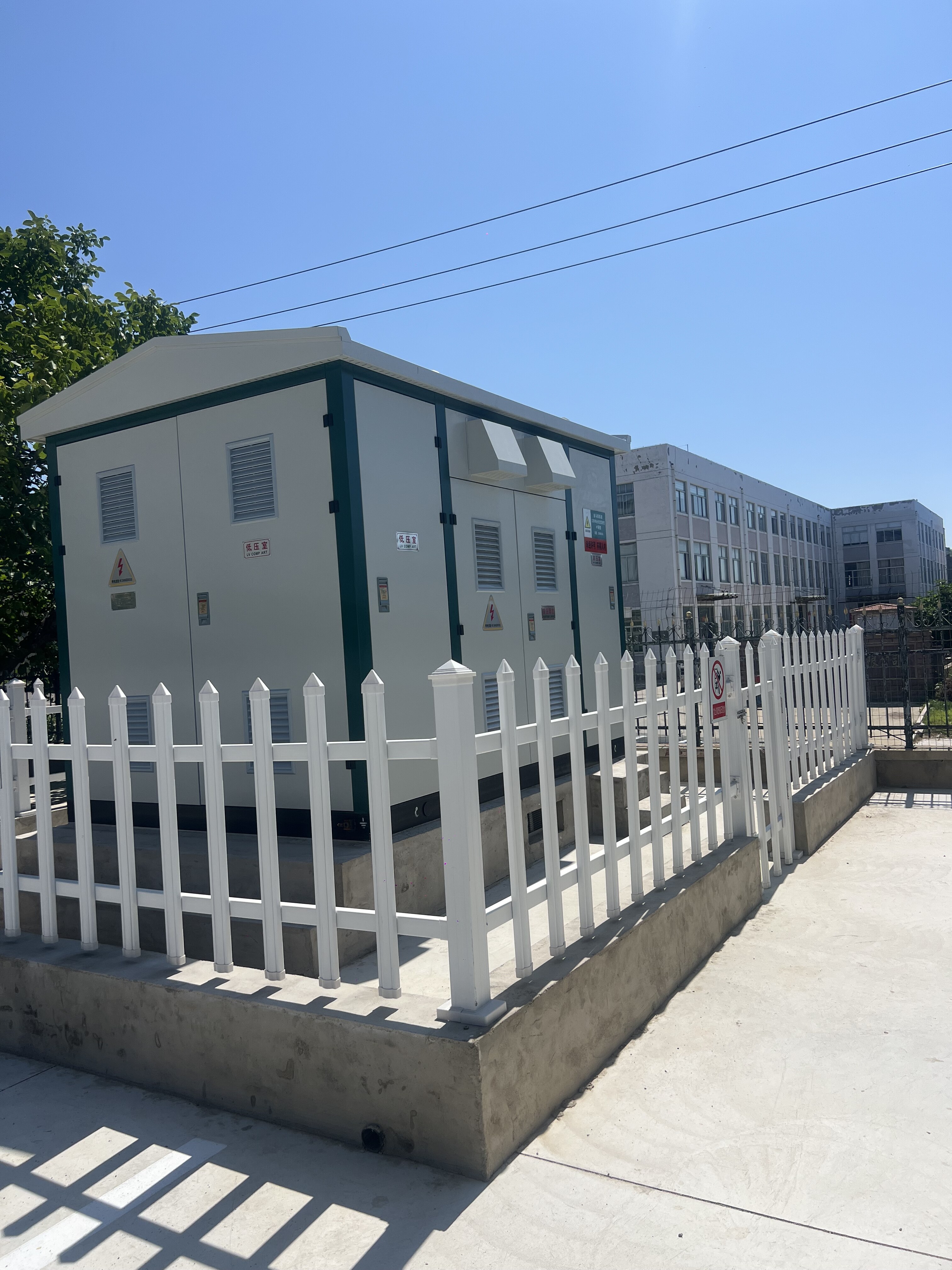 White energy storage container unit with green trim surrounded by white security fence