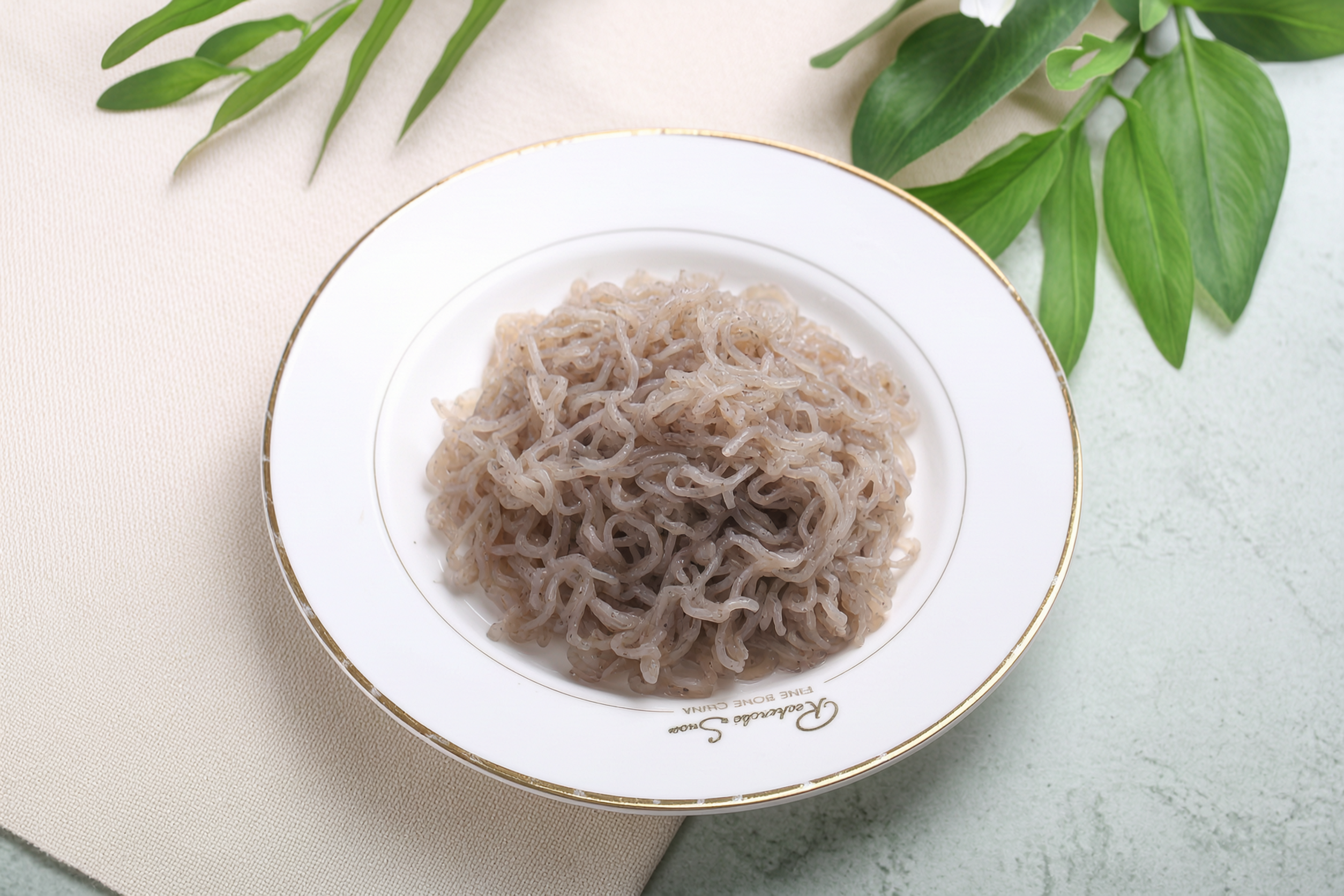 Seaweed konjac noodles on a white plate with green seaweed garnish