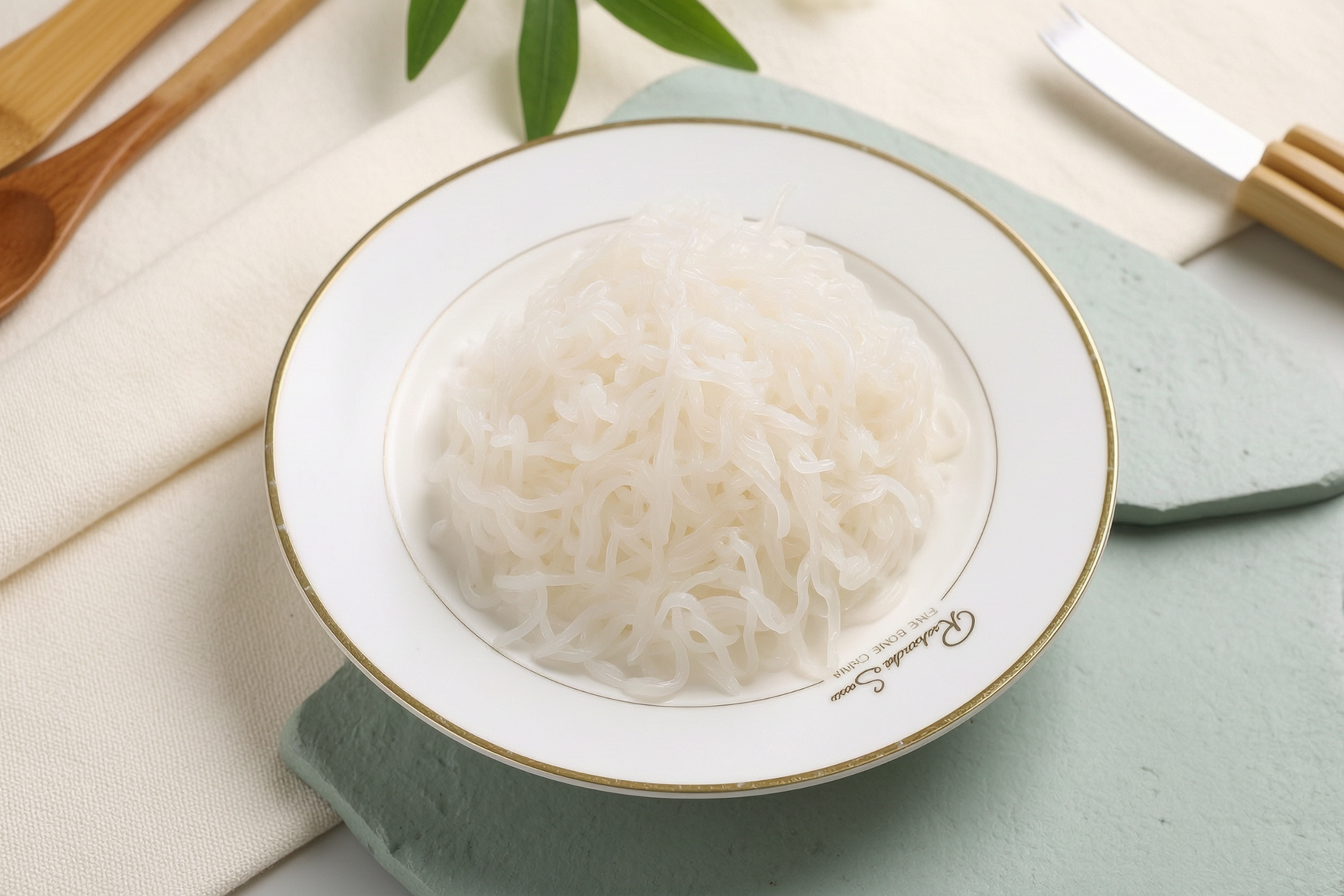Konjac spaghetti noodles on a white plate with tomato sauce and fresh basil leaves