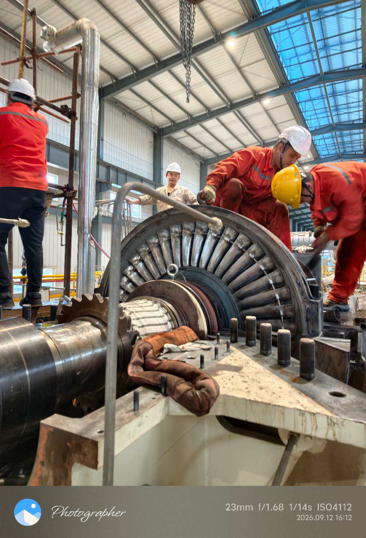 Teknisi bekerja di sekitar casing turbin terbuka saat pengangkatan rotor