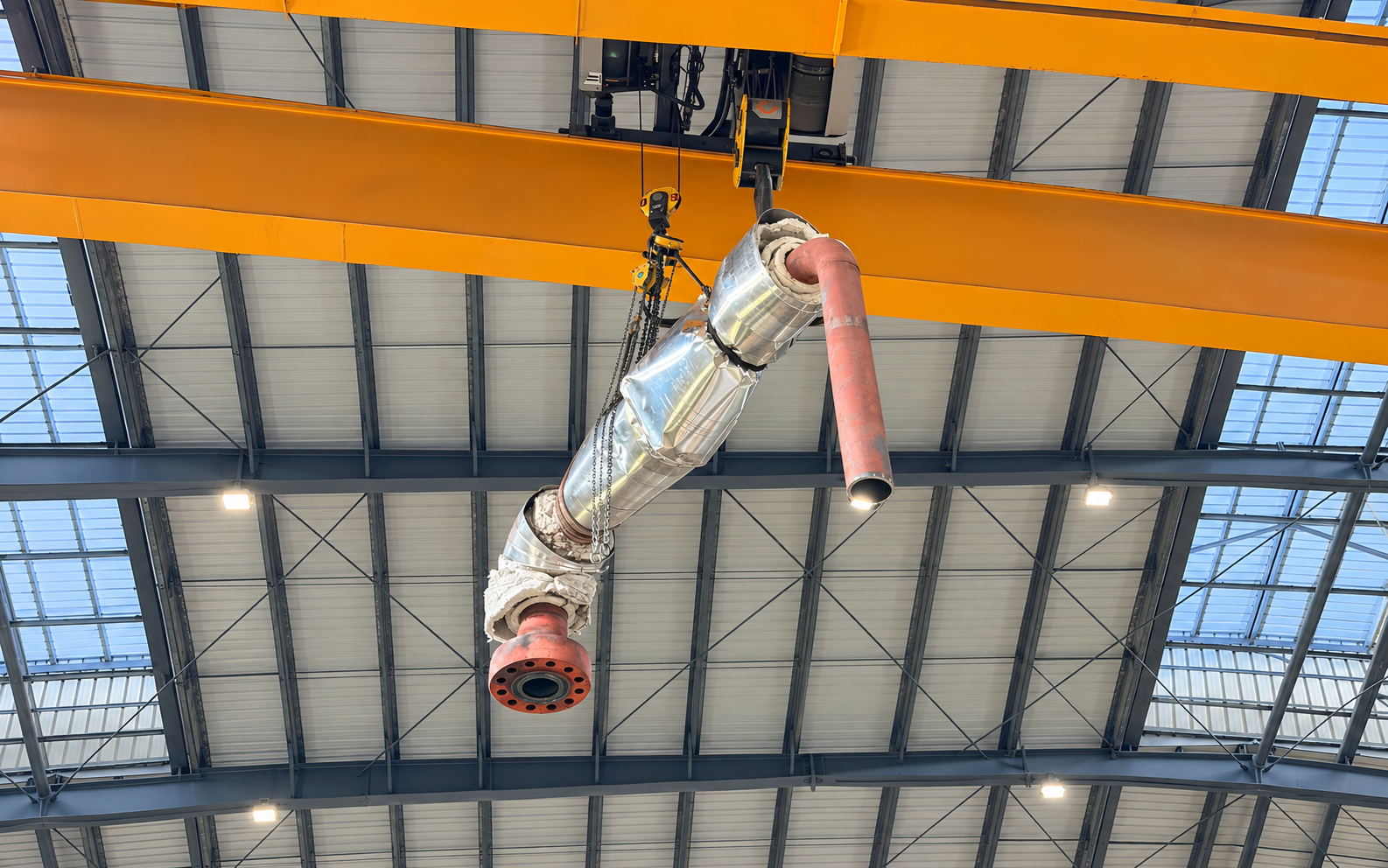 Pipa uap berinsulasi digantung dari crane overhead