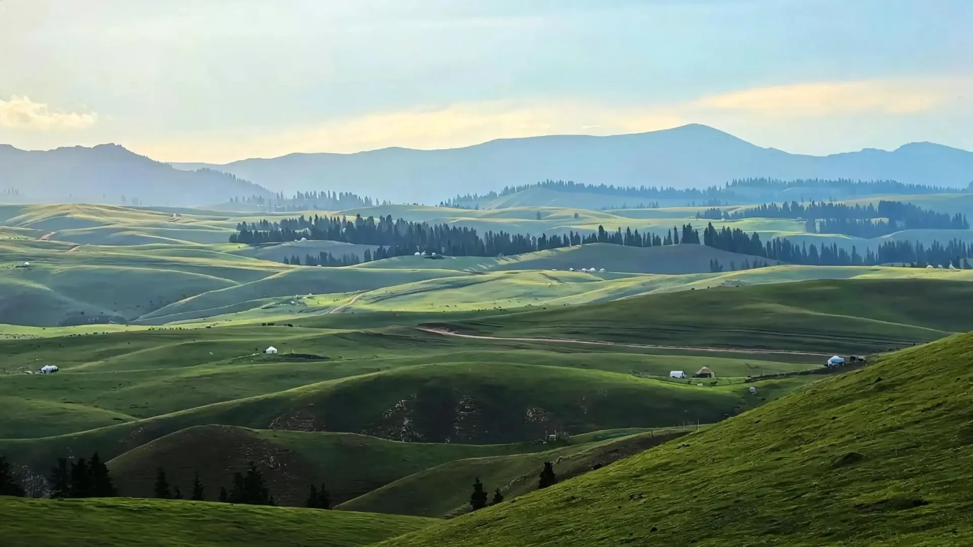 Highland scenery of rolling meadows and distant mountains bathed in morning light.
