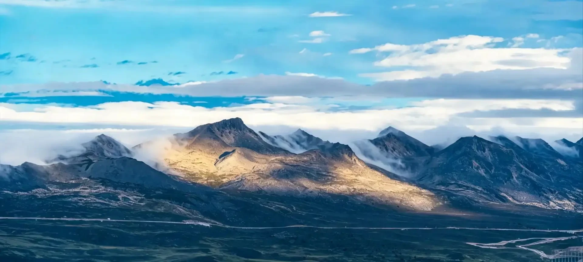 Snow-capped peaks glowing in the morning light above the sea of clouds