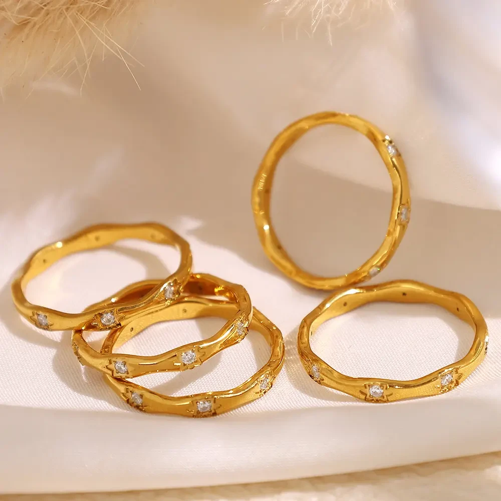 Gold stone-set rings with cubic zirconia arranged on cream silk fabric