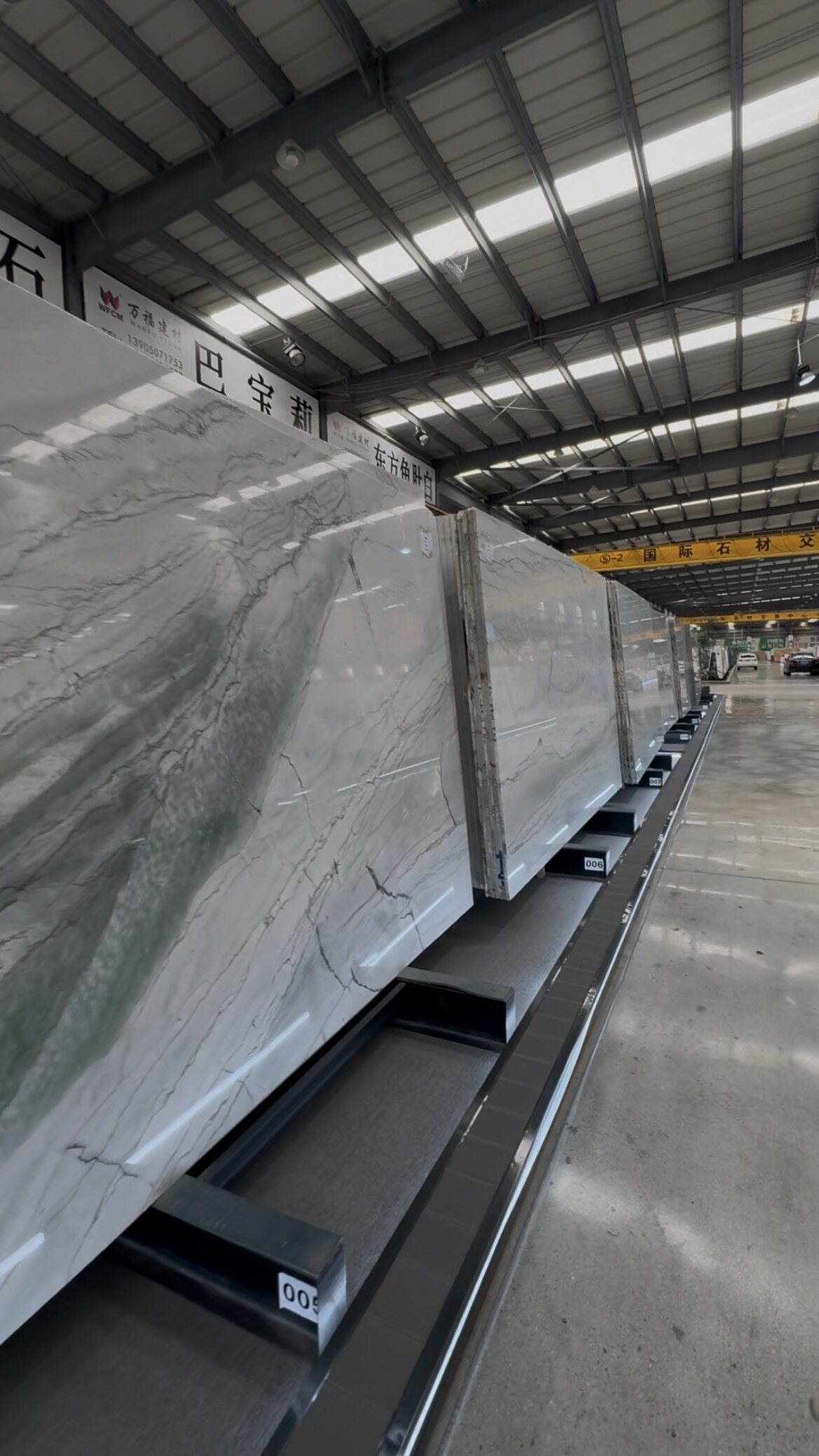 Rows of polished large-format marble slabs on display rails in the stone market
