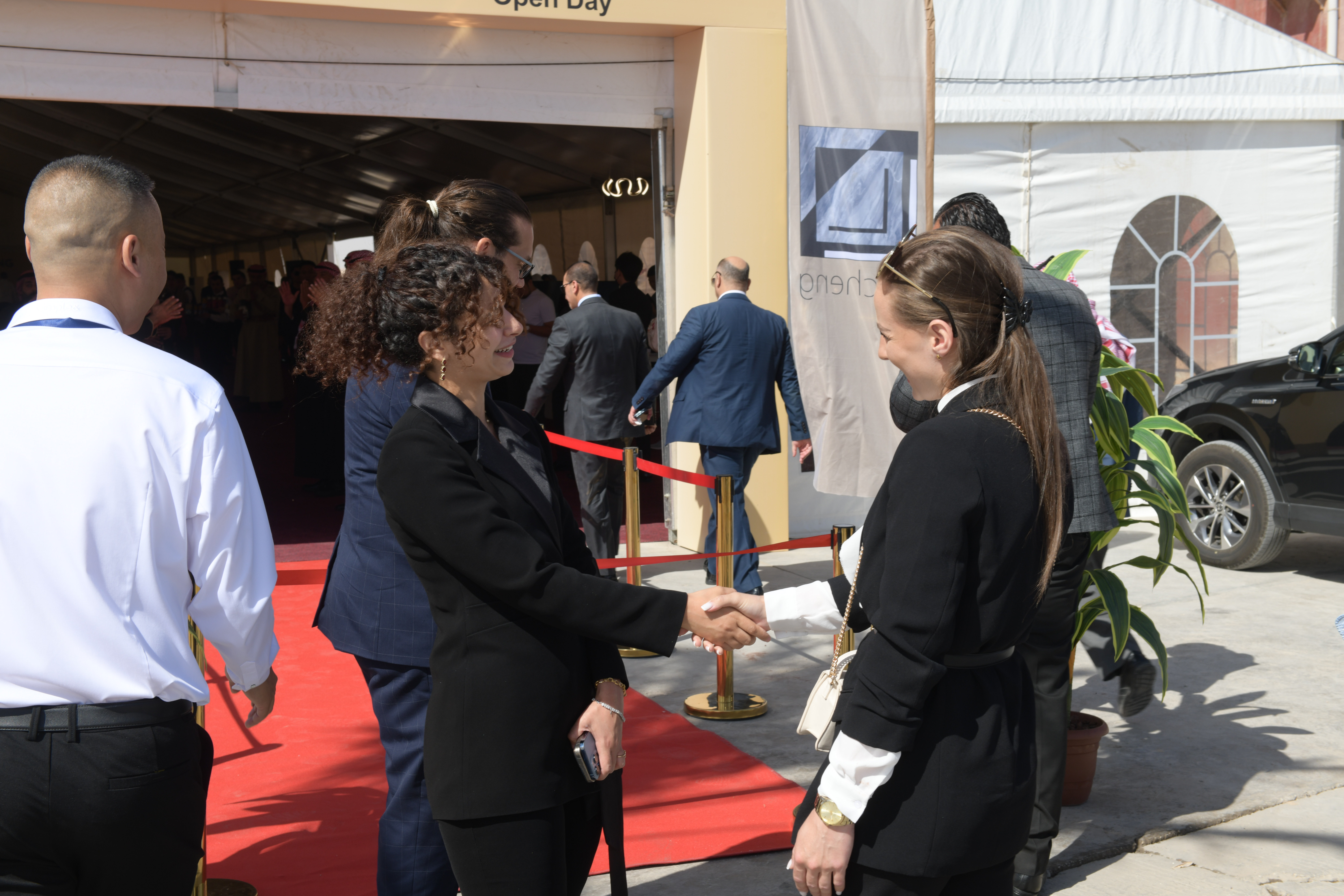 Team member welcoming a guest with a handshake on the red carpet at a factory open day