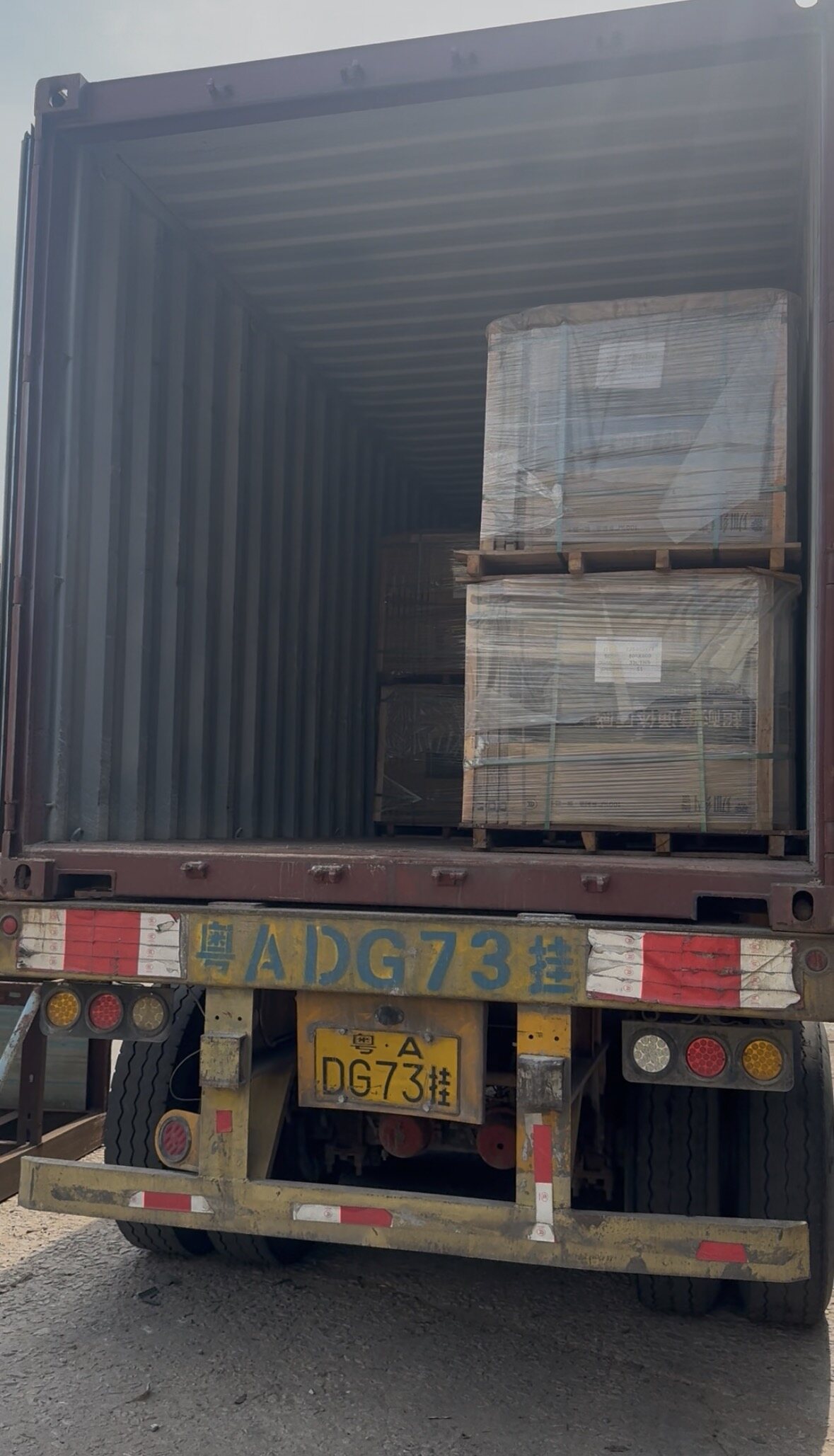 Open shipping container packed with strapped tile pallets ready for export