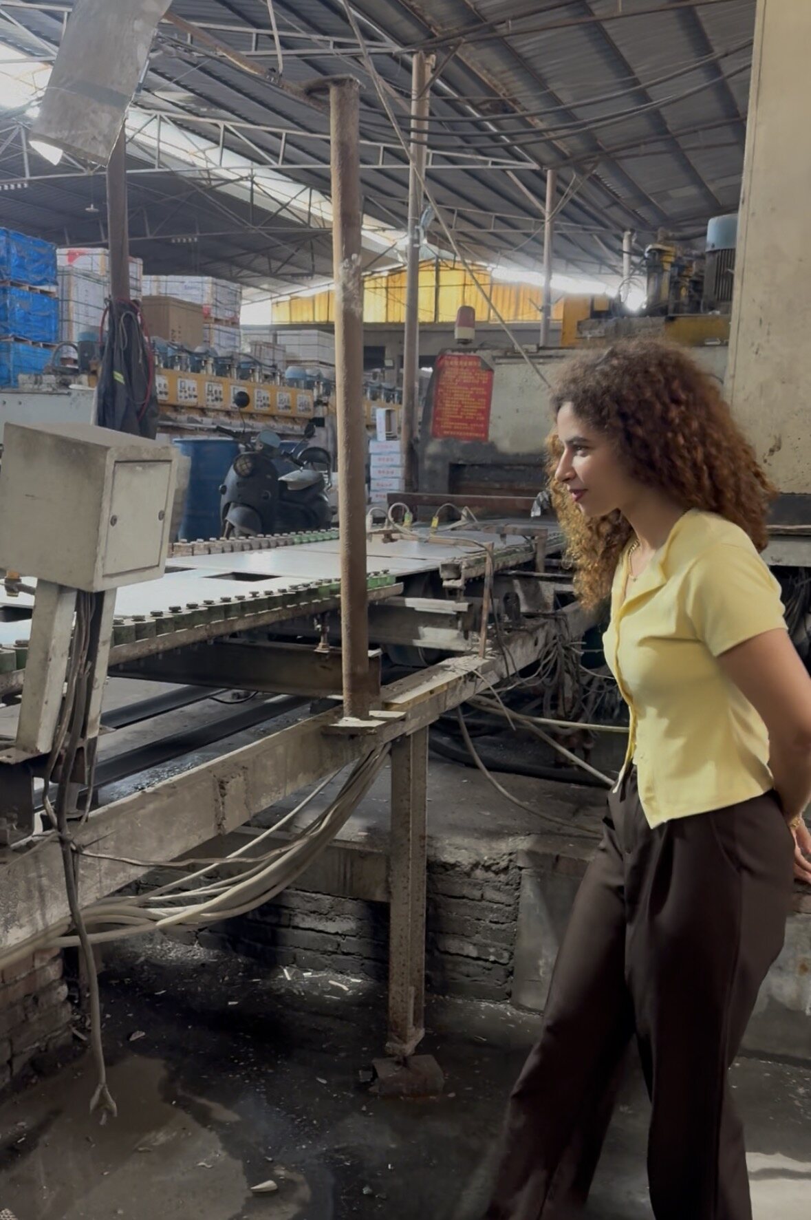 Team member inspecting a tile production line inside a partner factory