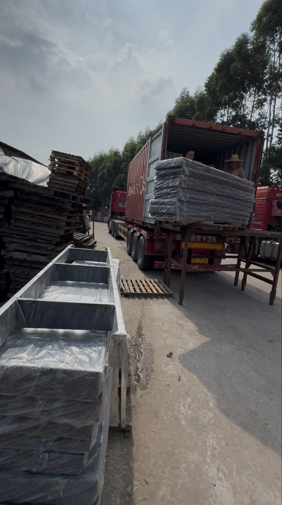 Wrapped tile pallets being loaded onto a container truck at the factory yard