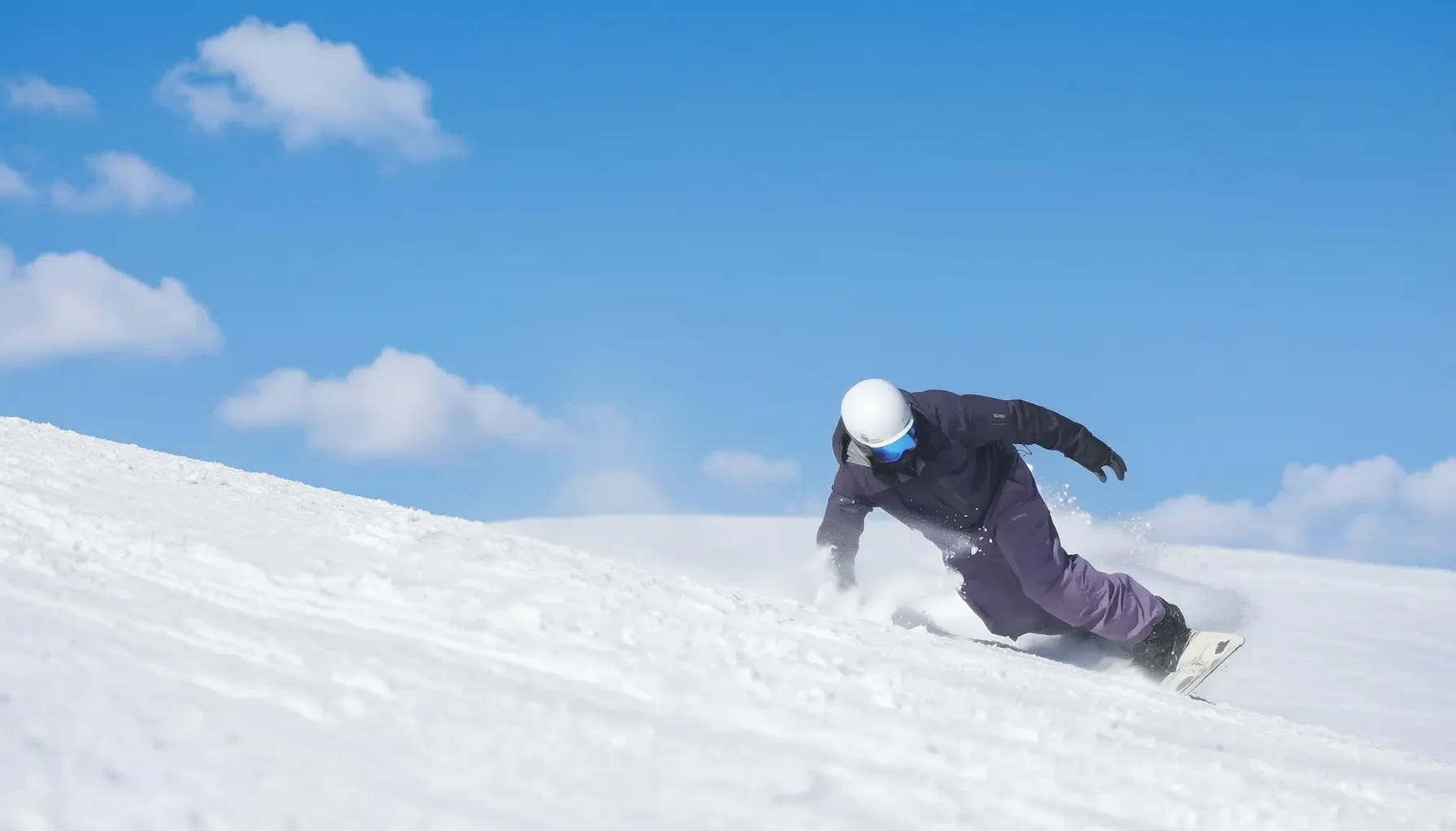 Snowboard instructor carving hard on a groomed slope with snow spray under a blue sky in Chongli