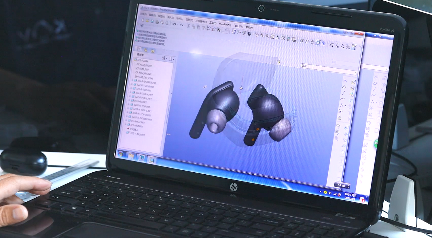 DBS R&D engineer designing wireless earphones using CAD software on laptop showing 3D model of TWS earbuds