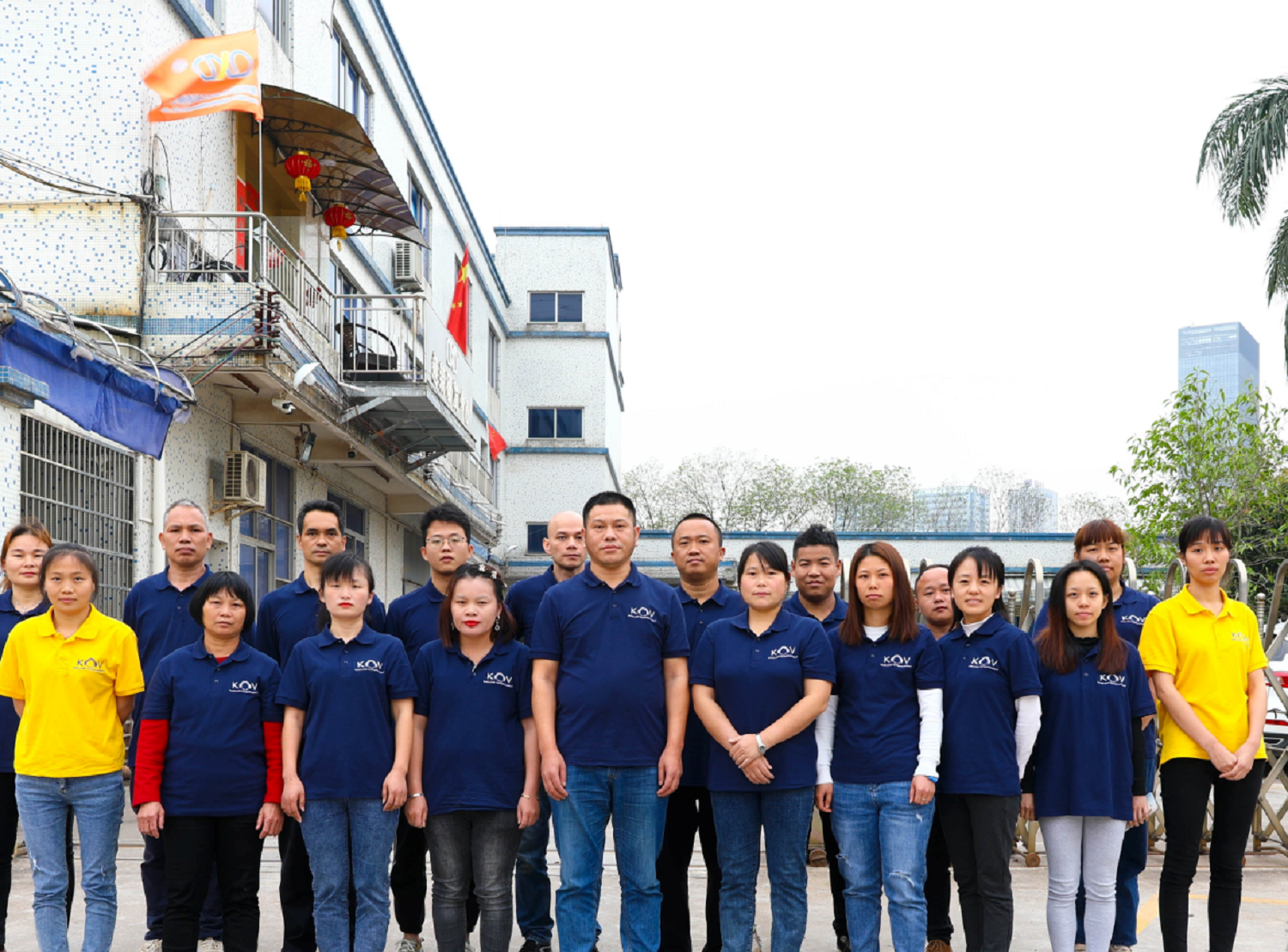 DBS professional team members in blue uniforms standing in front of factory building with Chinese flag