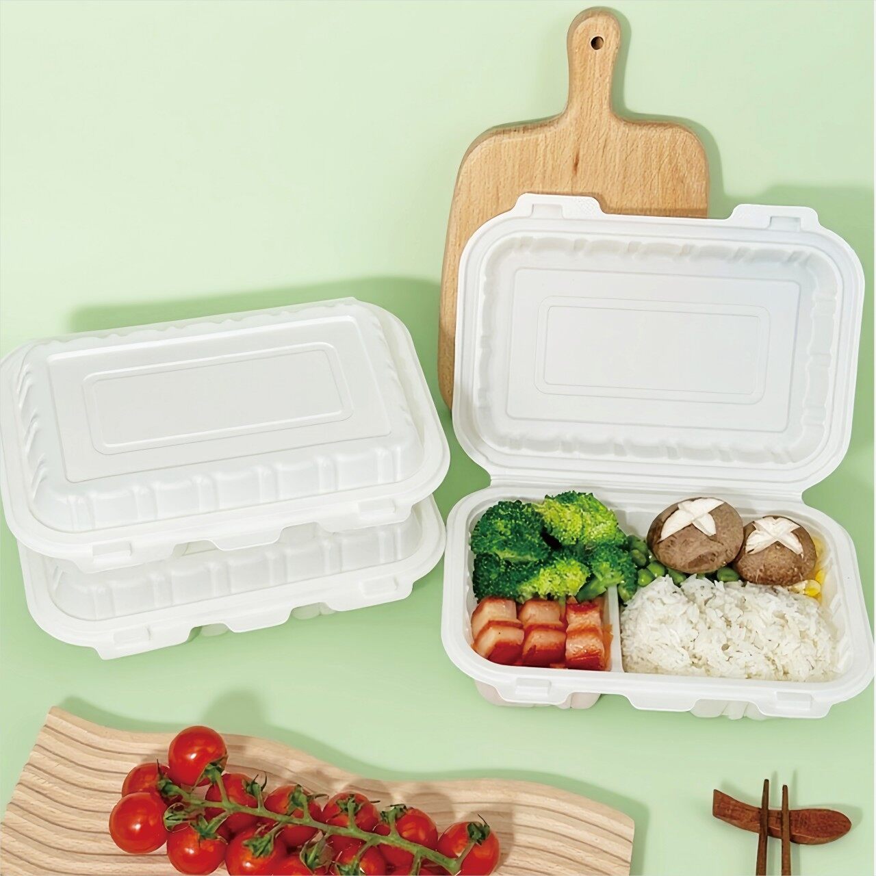 White hinged bamboo fiber lunch boxes, one open with rice, broccoli and braised pork inside